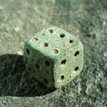 Dé séculaire antique sur fond rocheux