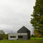 Maison modulaire moderne en béton et métal avec un grand arbre