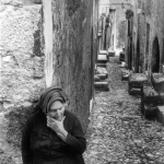 Vieille femme dans une ruelle pavée d'un village ancien