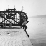 Homme au bord de l'eau près d'une grille industrielle