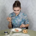Femme en train de manger un repas assise à une table