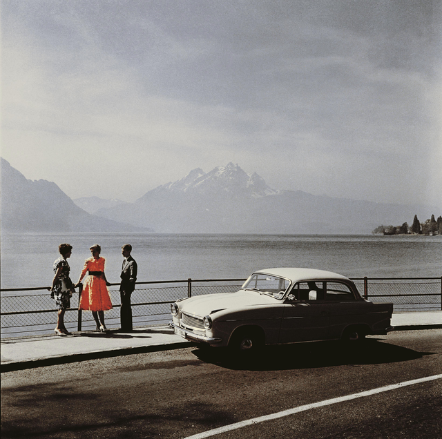 AKG249476.webp Trois adultes discutent près d'une voiture vintage au bord d'un lac – Image 1