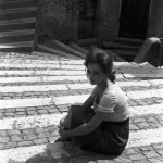 Femme assise sur des escaliers en pierre à l'extérieur.