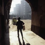 Homme dans une ruelle avec un seau sous une arche