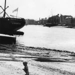 Enfant jouant sur une plage urbaine près d'un navire