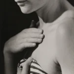 Portrait en noir et blanc d'une femme touchant son épaule.