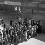 Queue devant une billetterie avec train en arrière-plan