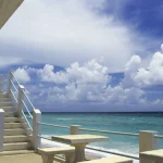 Escalier menant à une plage sous un ciel partiellement nuageux