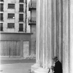 Homme lisant près de colonnes massives devant un immeuble