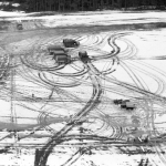 Champs enneigé avec camions de chantier et traces de pneus