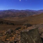 Ciel étoilé au-dessus de montages désertiques avec pétroglyphes sur une pierre