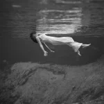 Femme flottant sous l'eau en robe blanche