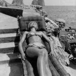 Femme se prélassant au soleil sur une chaise longue près de la mer