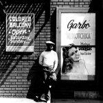 Homme devant une affiche de cinéma et un panneau de balcon séparé