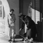 Femme et homme avec chien devant une entrée