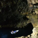 Personne dans une barque explorant une grotte marine