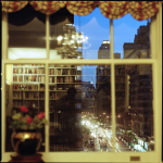 Vue nocturne d'une bibliothèque à travers une fenêtre donnant sur une ville animée