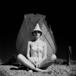 Femme en maillot de bain assise devant un bateau