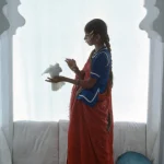 Femme en sari avec une colombe dans une alcôve traditionnelle