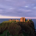 Château en ruines sur une falaise au coucher du soleil