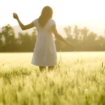 Femme dans un champ au coucher du soleil