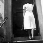 Femme montant des marches vers une porte.