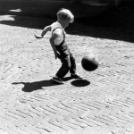 Enfant jouant avec un ballon dans la rue