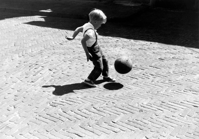 AKG3802240.webp Enfant jouant avec un ballon dans la rue – Image 1