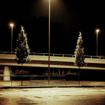 Lumières de rue sous la pluie nocturne à côté d'un pont.