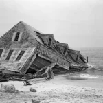 Maison effondrée sur une plage.