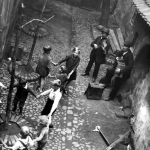 Enfants dansant en cercle avec musique dans une cour pavée