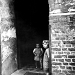 Deux enfants dans une entrée sombre en brique