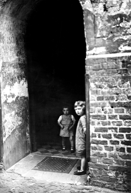 AKG3969623.webp Deux enfants dans une entrée sombre en brique – Image 1