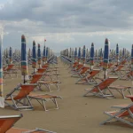Plage Déserte avec Chaises Longues et Parapluies Fermés