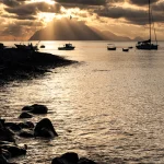 Coucher de soleil sur une baie avec des bateaux et une montagne en arrière-plan