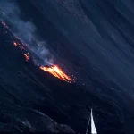 Voilier proche d'une éruption volcanique nocturne