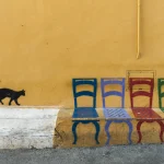 Chat et chaises colorées peintes sur un mur jaune