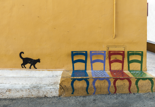 AKG4042721.webp Chat et chaises colorées peintes sur un mur jaune – Image 1