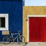 Maison colorée avec vélo devant une porte jaune et rouge