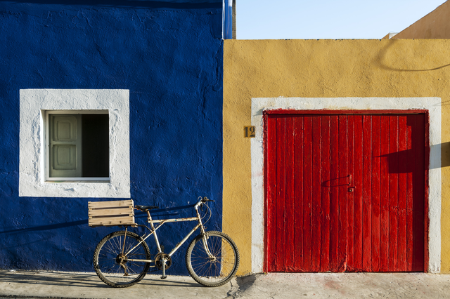 AKG4042722.webp Maison colorée avec vélo devant une porte jaune et rouge – Image 1