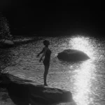 Personne debout près d'un lac au coucher du soleil