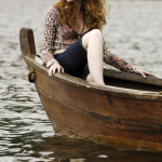 Femme rousse sur une barque en bois