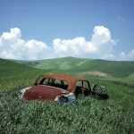 Voiture abandonnée dans un paysage vallonné