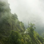 Chemin brumeux à flanc de montagne avec pylône électrique