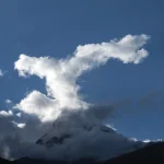 Nuages formant des silhouettes impressionnantes au-dessus d'une montagne