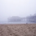 Plage brumeuse avec une jetée en arrière-plan