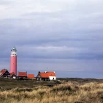 Phare sur une côte avec maisons - paysage nuageux