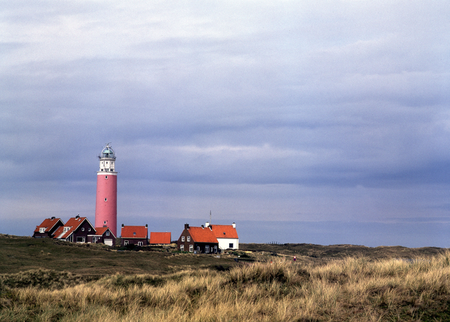 AKG410765.webp Phare sur une côte avec maisons - paysage nuageux – Image 1