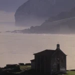 Petite chapelle au bord de la mer avec falaises en arrière-plan