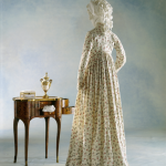 Femme en robe d'époque à côté d'une table ancienne